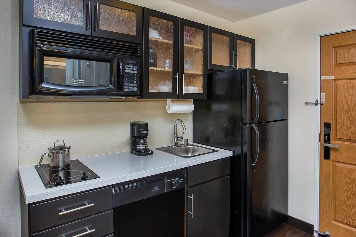 A compact kitchen with a microwave, coffee maker, and a refrigerator.