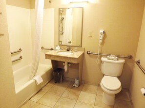 A bathroom with a bathtub, toilet, sink, and a hand dryer. - Candlewood Suites Warner Robins/Robins AFB by IHG (Warner Robins)