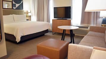 Una habitación de hotel con una cama grande, televisión, una mesita y un sofá.