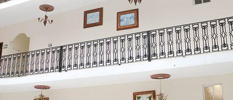 A multi-level interior with a tiled floor, balconies with iron railings, and ceiling fans.
