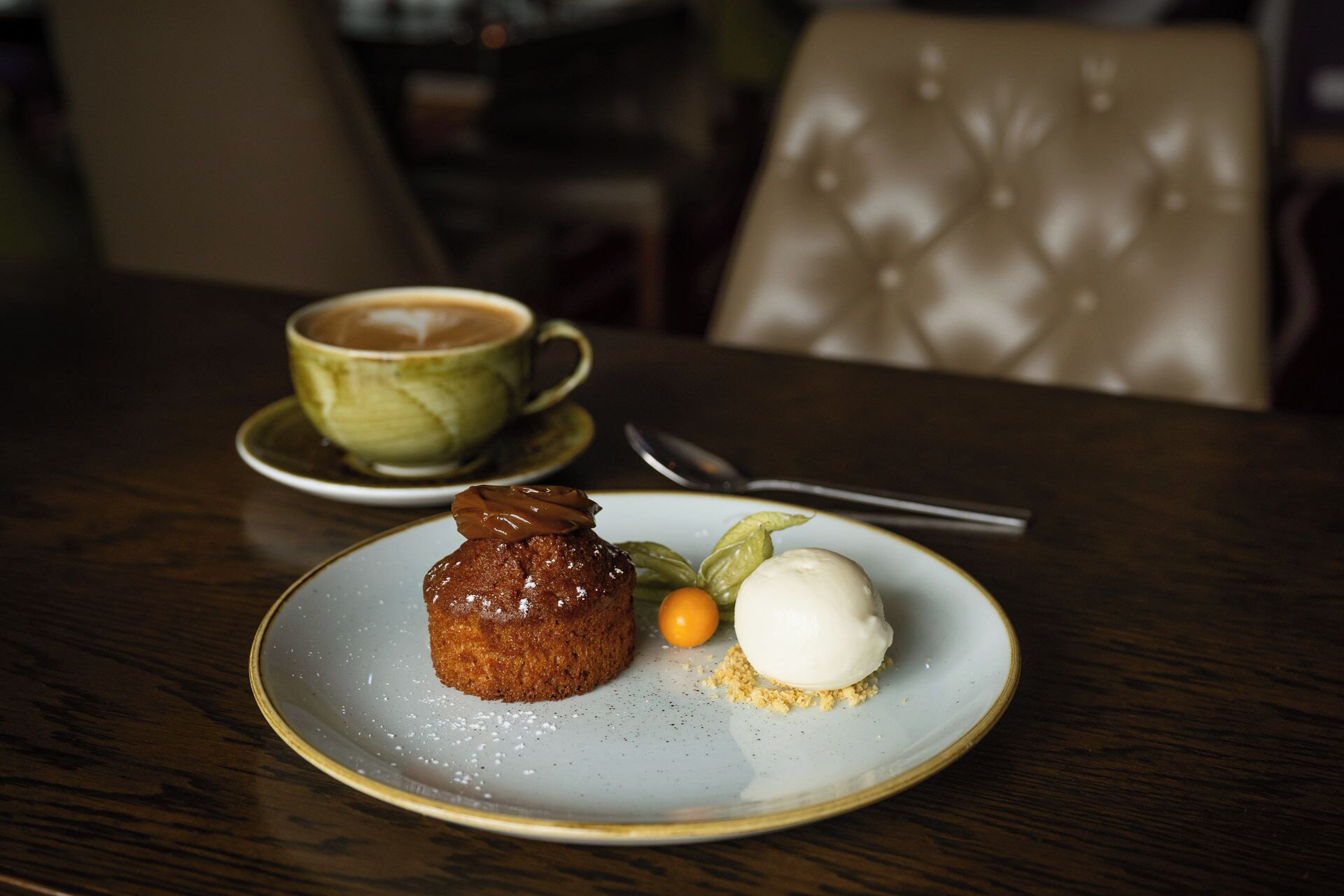 A dessert plate with a cake, a scoop of ice cream, and a small orange on a ceramic plate.