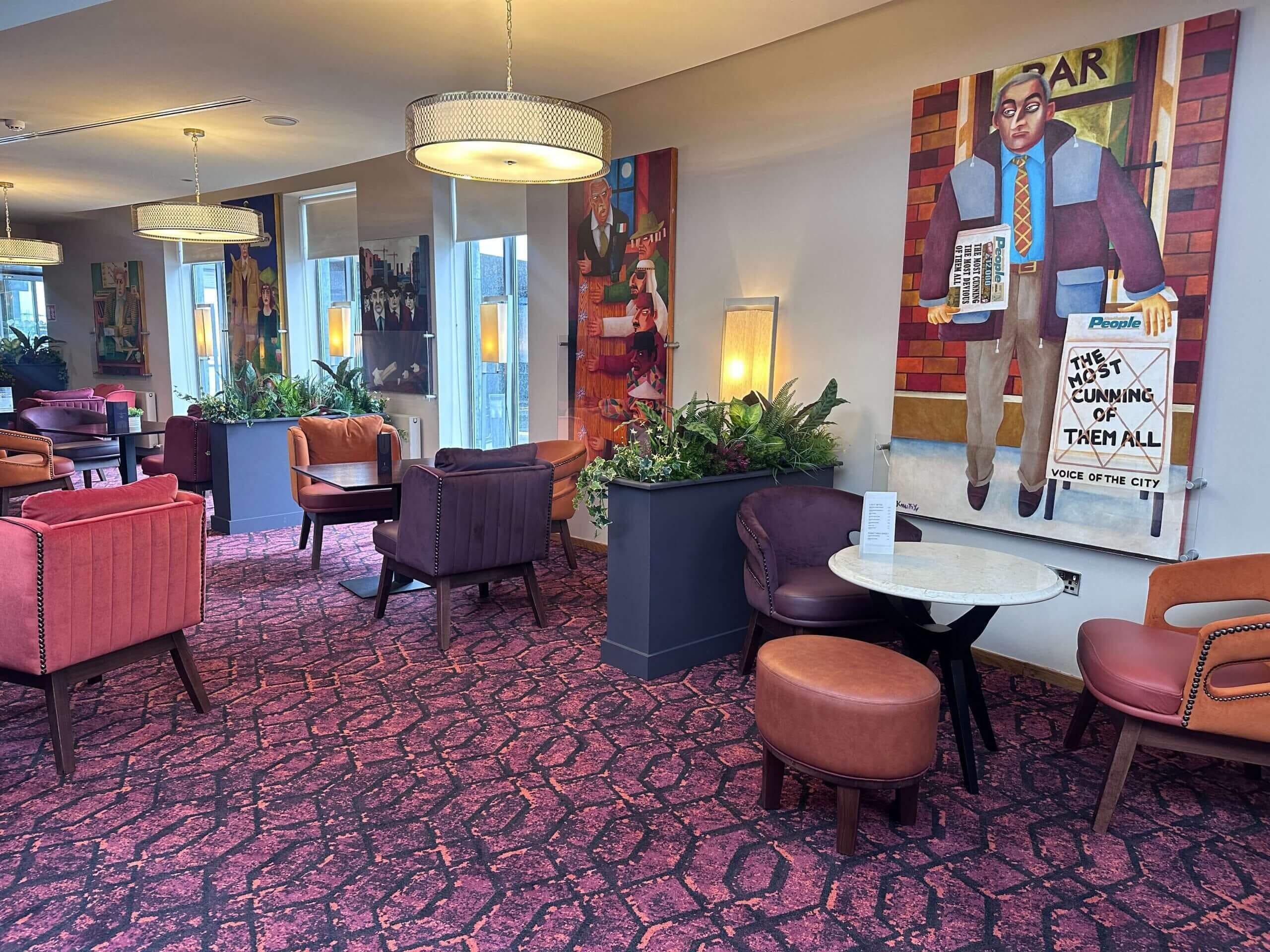 Rebedor d'hotel amb zones d'estar, un bar i obres d'art a les parets.