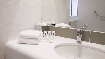 A modern bathroom with a white sink, a mirror, and neatly folded white towels.
