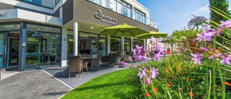 A restaurant named "Seasons Bar & Brasserie" with outdoor seating and a well-maintained garden.