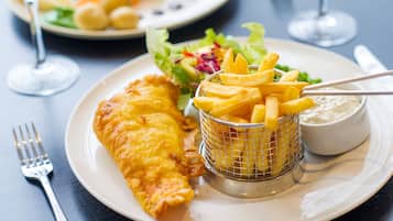 A plate with fish and chips, a small bowl of tartar sauce, and a side salad.