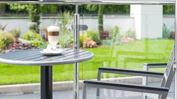 Una mesa redonda con superficie de vidrio y una silla con estructura metálica.