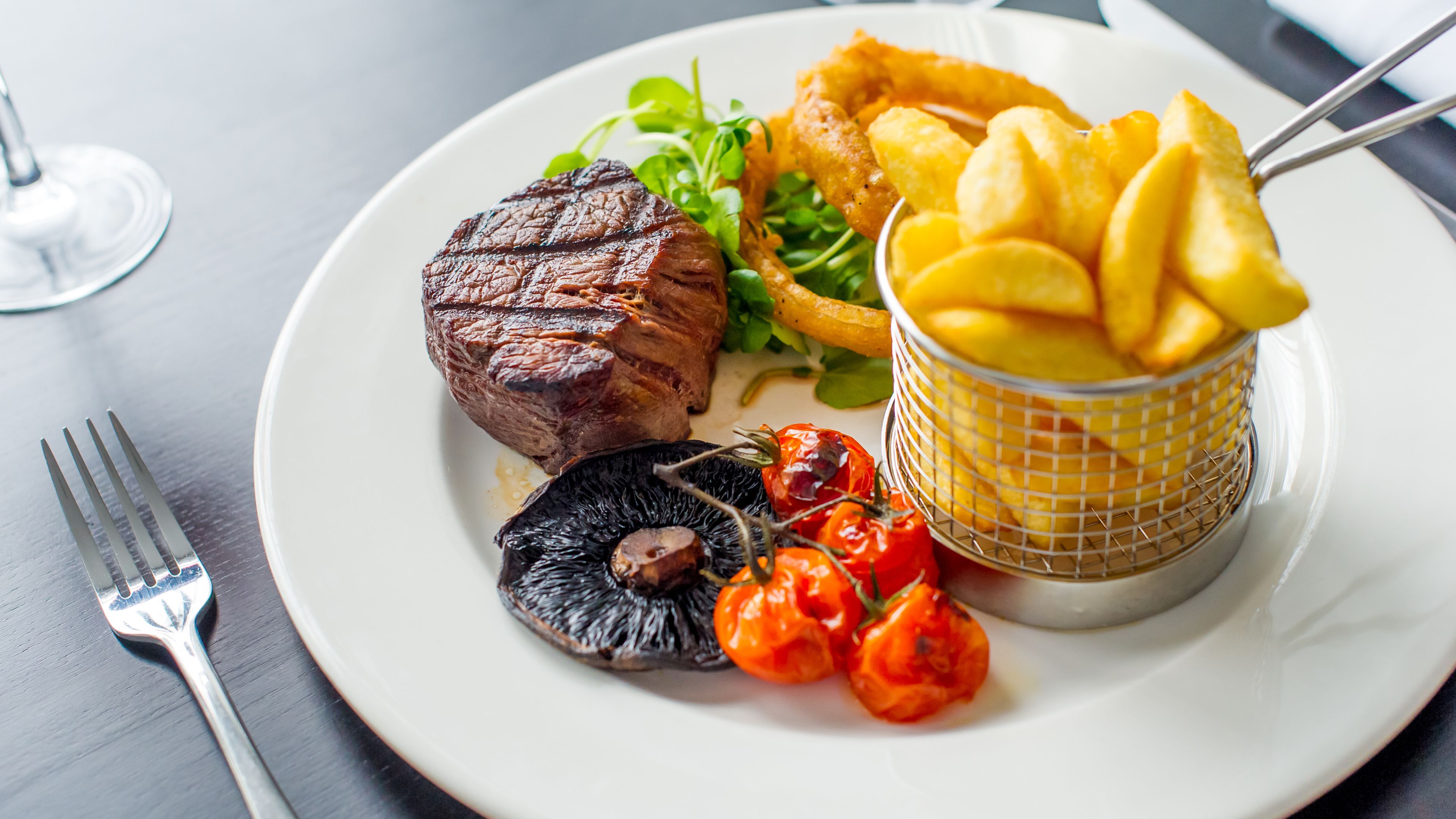 Une assiette avec un steak, des frites, des champignons et des tomates cerises.