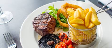 Une assiette avec un steak, des frites, des champignons et des tomates cerises.