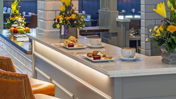 A modern bar area with a marble countertop, gold pendant lights, and a variety of flowers. - City North Hotel and Conference Centre (Gormanston)