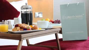 A breakfast setup with croissants, orange juice, and a coffee pot on a table. A City North Hotel sign is visible.