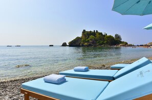 Playa privada, arena negra, sillas reclinables de playa, sombrillas