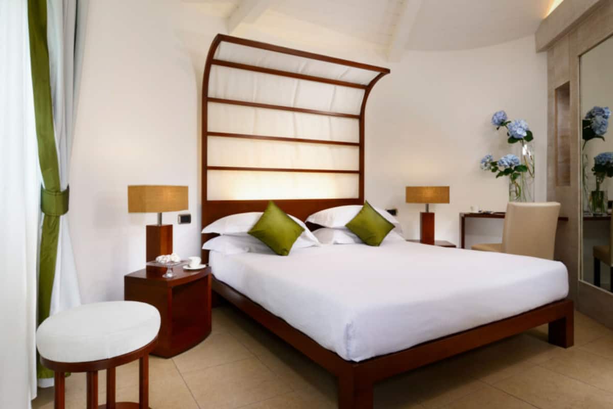 A neatly arranged hotel room with a large bed, two bedside tables, a chair, and a nightstand.