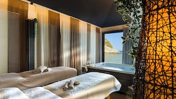 A spa room with a large window, a hot tub, and a view of the sea.
