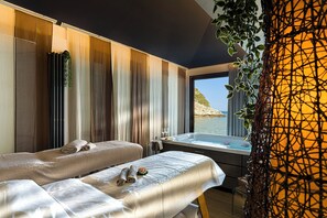 Spa-huone, jossa on suuri ikkuna, poreallas ja näkymä merelle.