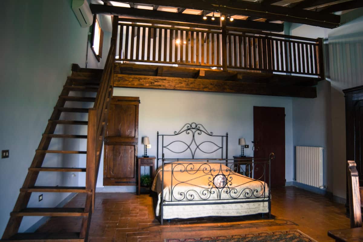Un dormitorio con una escalera de madera, un marco de cama de metal y una puerta de madera.