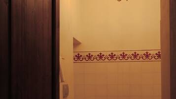Un baño con puerta de madera, una bañera blanca, un inodoro blanco, un bidé y una araña.