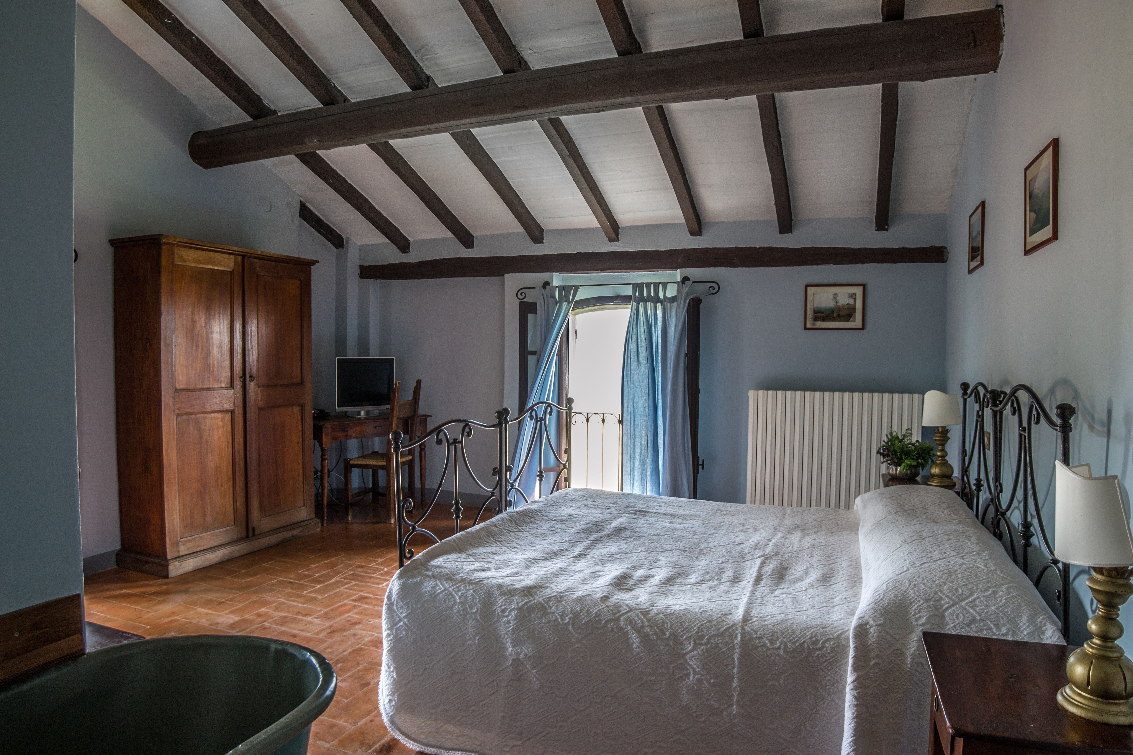 A bedroom with a bed, wooden wardrobe, and a desk with a chair.