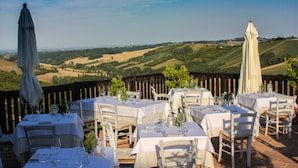 Un área de comedor al aire libre con mesas dispuestas para una comida, con vistas a un paisaje pintoresco.