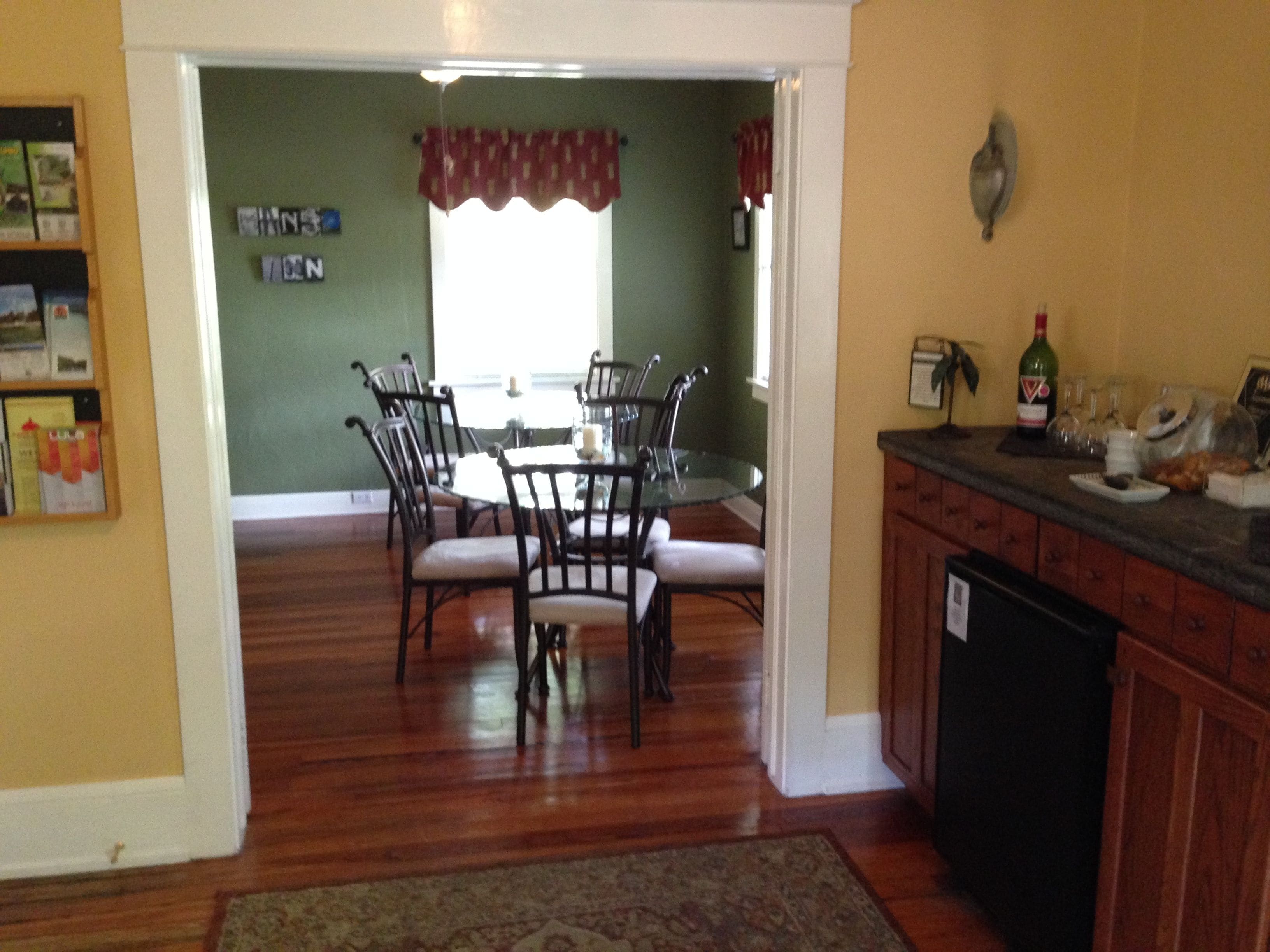 A dining area with a table and chairs, a kitchen with a dishwasher, and a window with curtains.