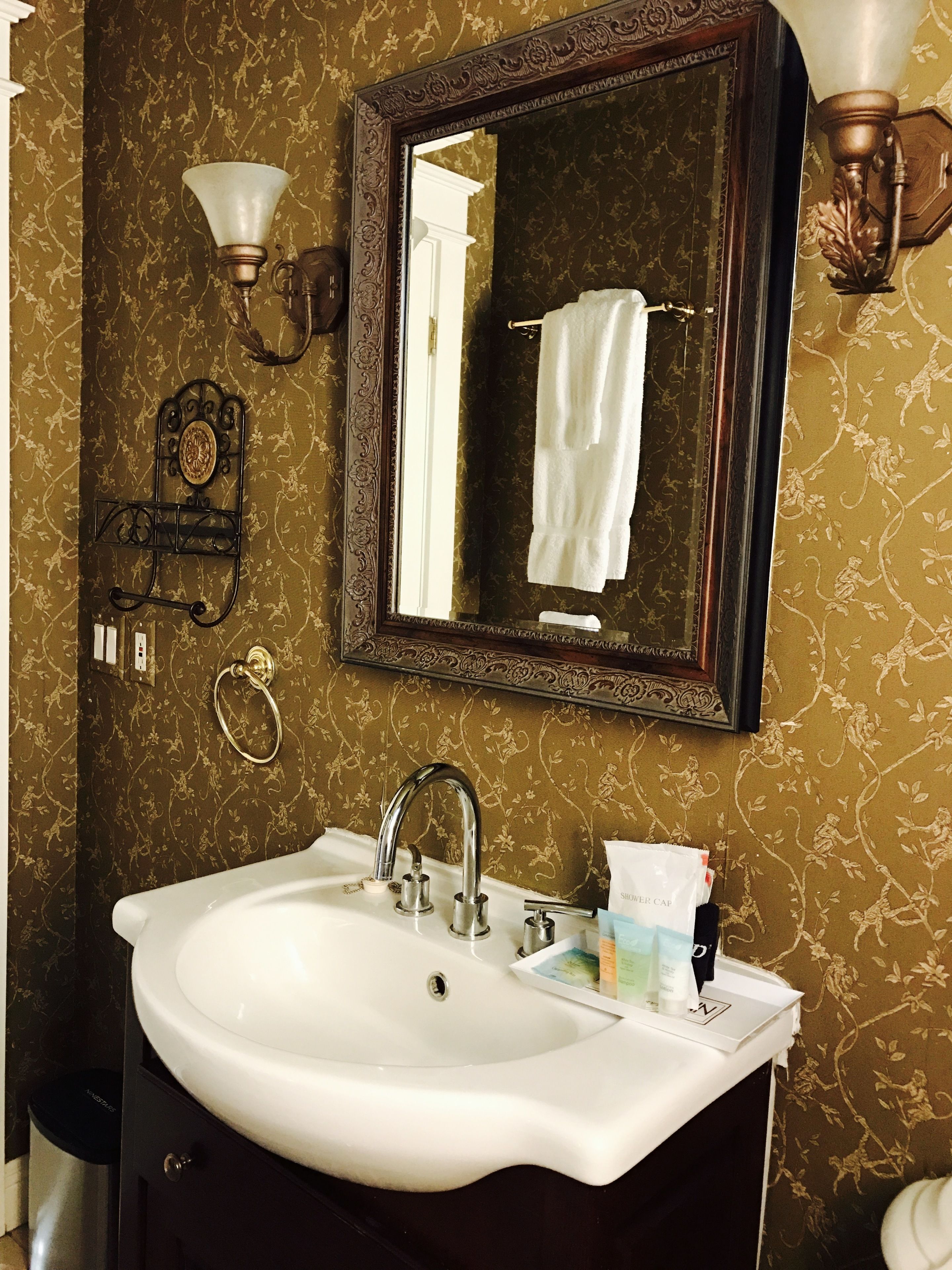 Une salle de bain avec un lavabo blanc, un miroir et une serviette suspendue à un porte-serviettes.