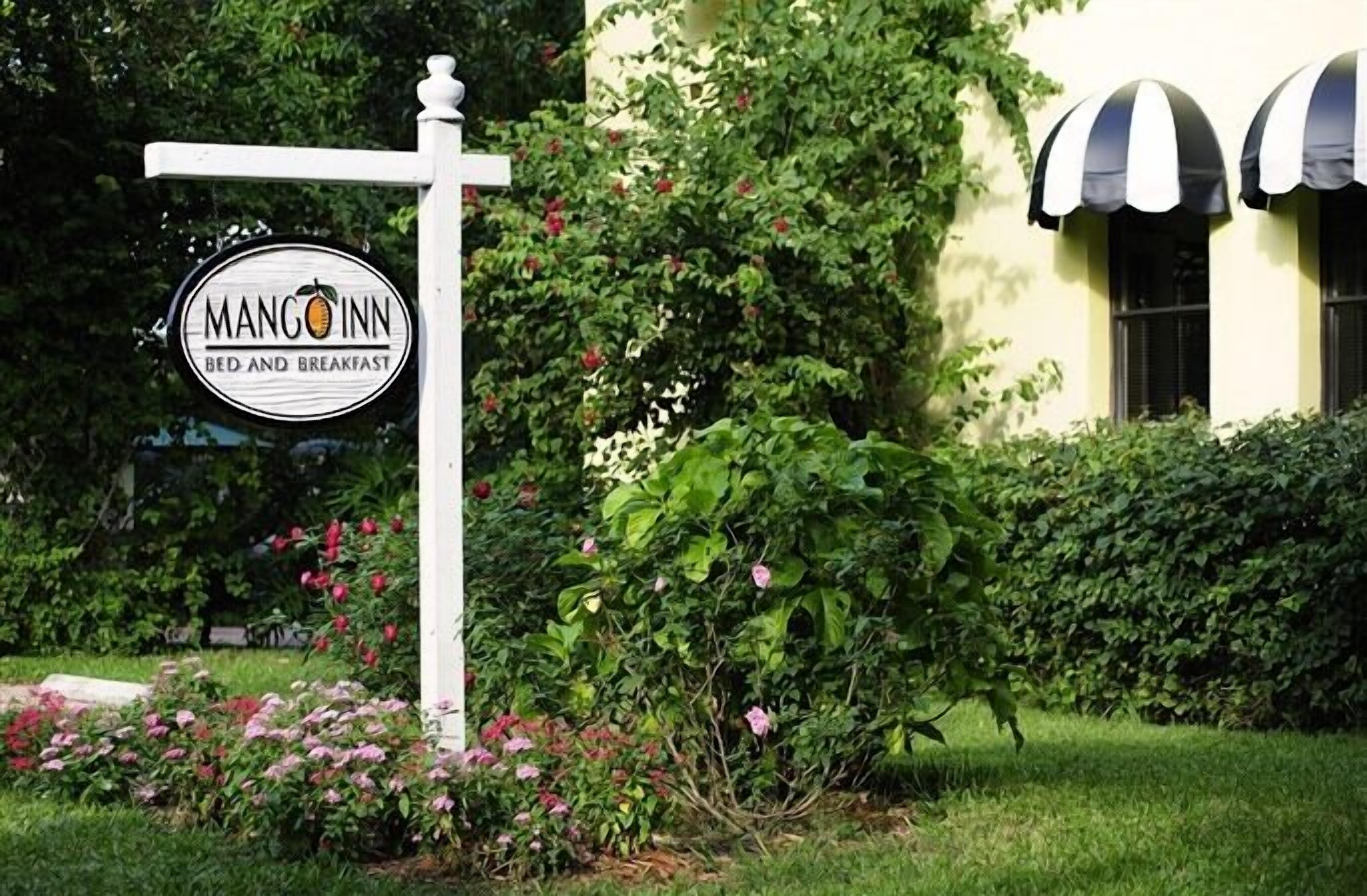 Señal de Mango Inn Bed and Breakfast, con un poste blanco y un logotipo circular.