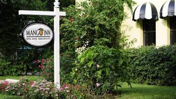 Señal de Mango Inn Bed and Breakfast, con un poste blanco y un logotipo circular.