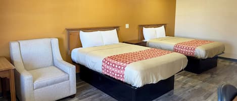 Habitación de hotel con dos camas, un sofá y piso de madera.