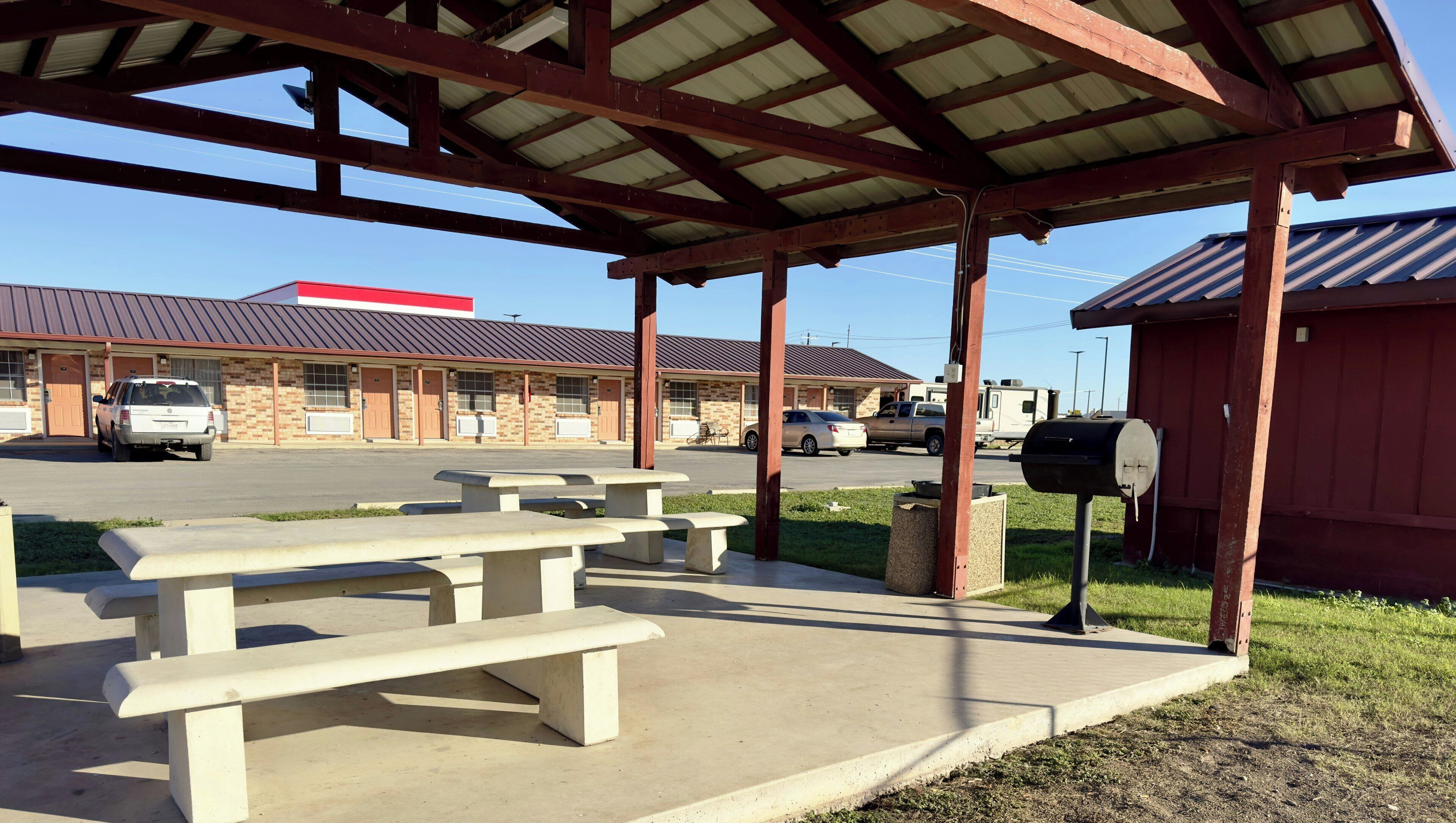 A covered picnic area with benches, a grill, and a mailbox.