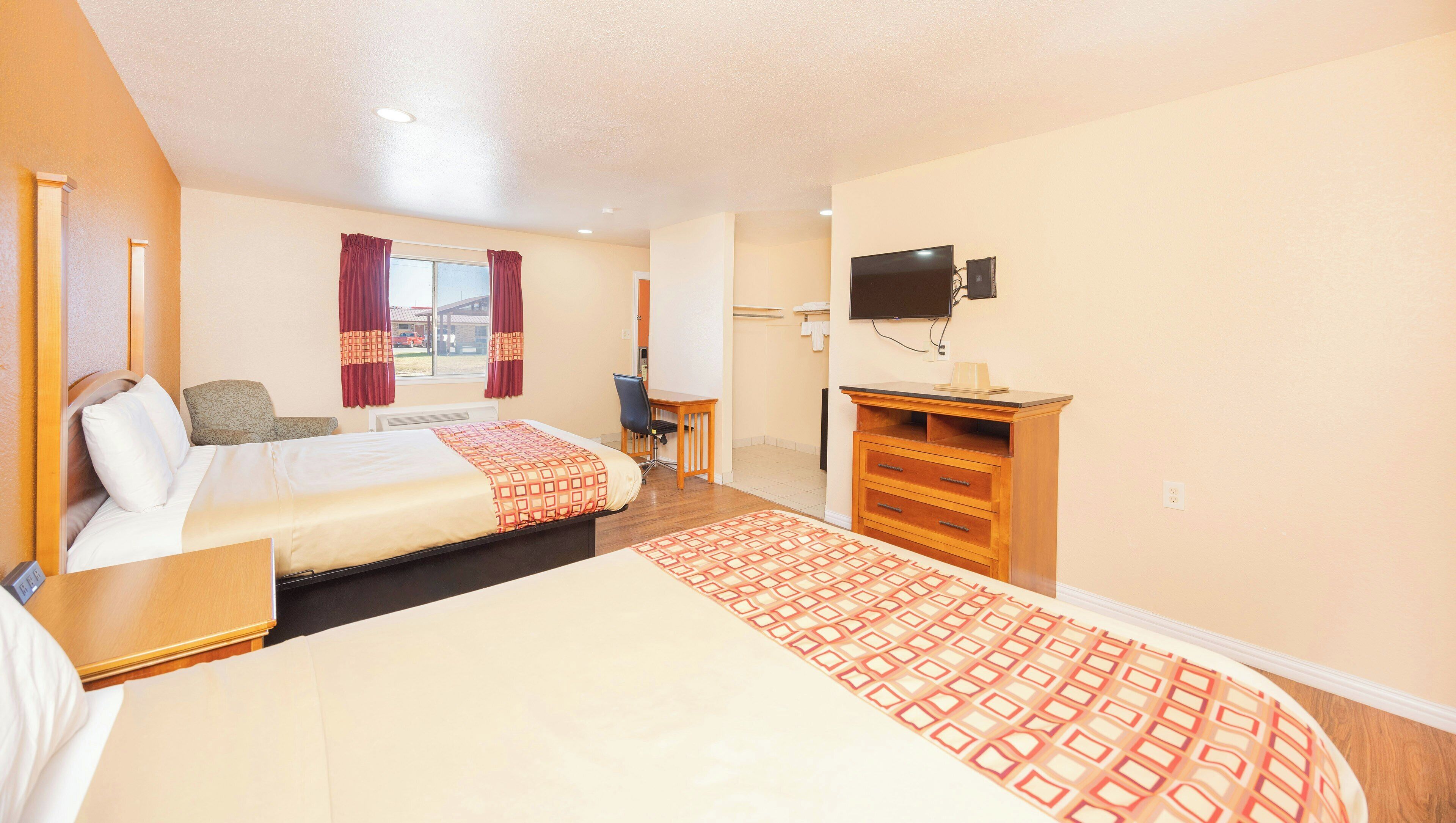 Una habitación de hotel con cama, escritorio, silla, televisor y armario.