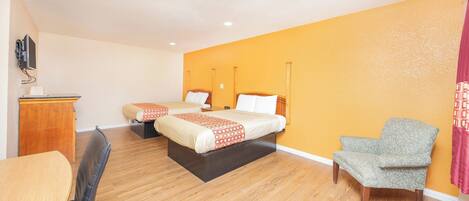 A hotel room with two beds, a desk, a chair, and a television mounted on the wall.