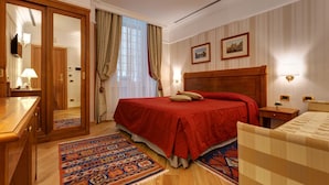 A hotel room with a large bed, a wooden wardrobe, a desk, and a nightstand. - ResidenzaRomaCentro (Rome)