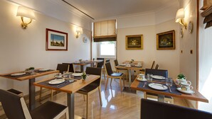 A dining area with multiple tables and chairs, equipped with table settings and wall-mounted lamps. - ResidenzaRomaCentro (Rome)