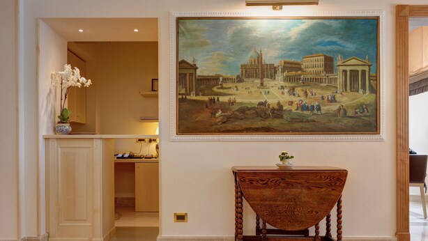 A lobby with a large classical painting, a wooden table, and a vase of flowers. - ResidenzaRomaCentro (Rome)