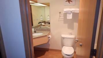 A bathroom with a sink, mirror, toilet, and a towel rack.