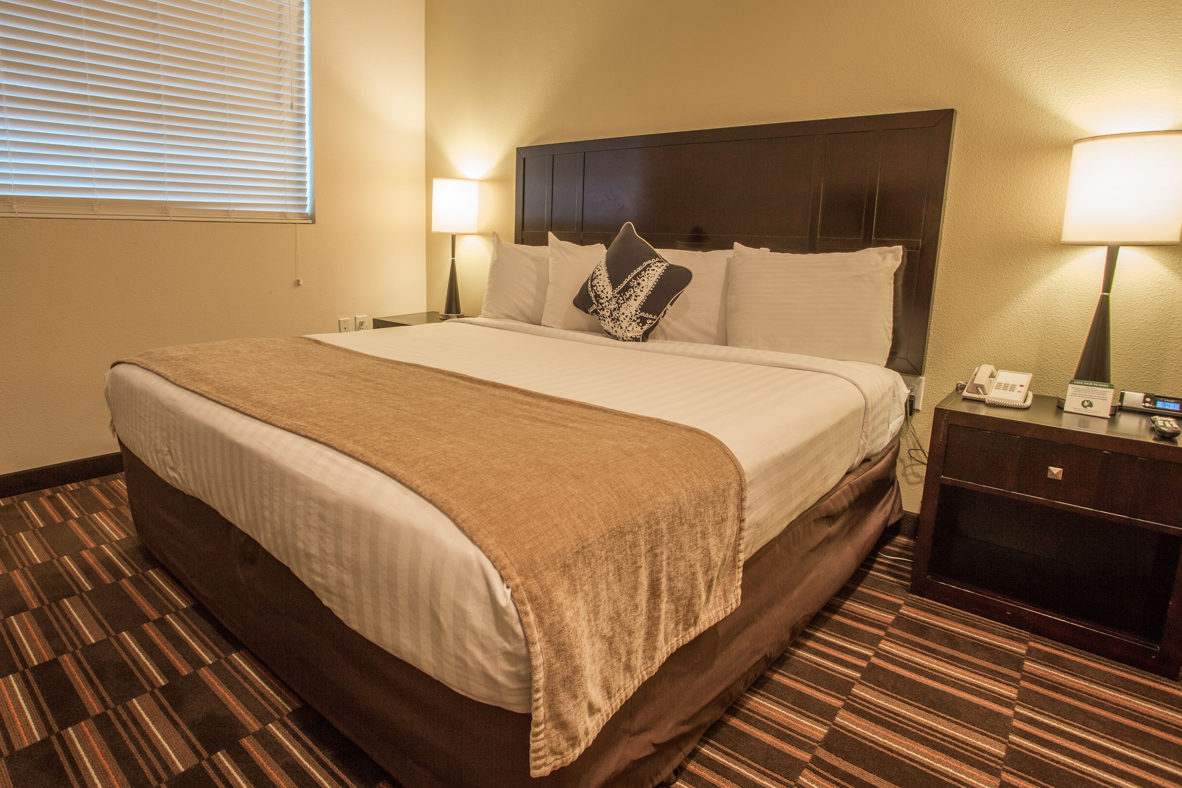 Habitación de hotel con una cama grande, dos mesitas de noche, una lámpara y un teléfono.