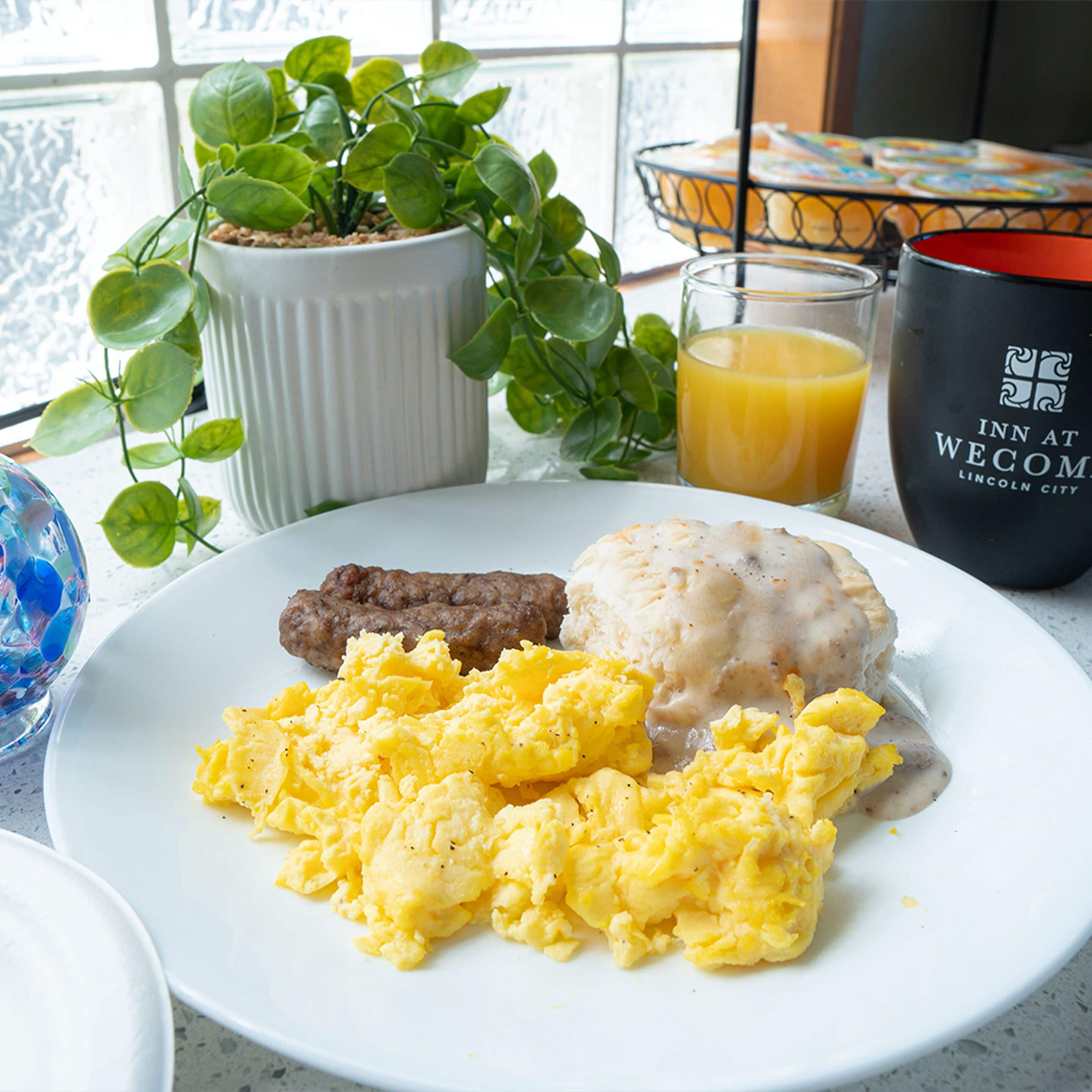 A breakfast plate with scrambled eggs, sausage, and biscuits.