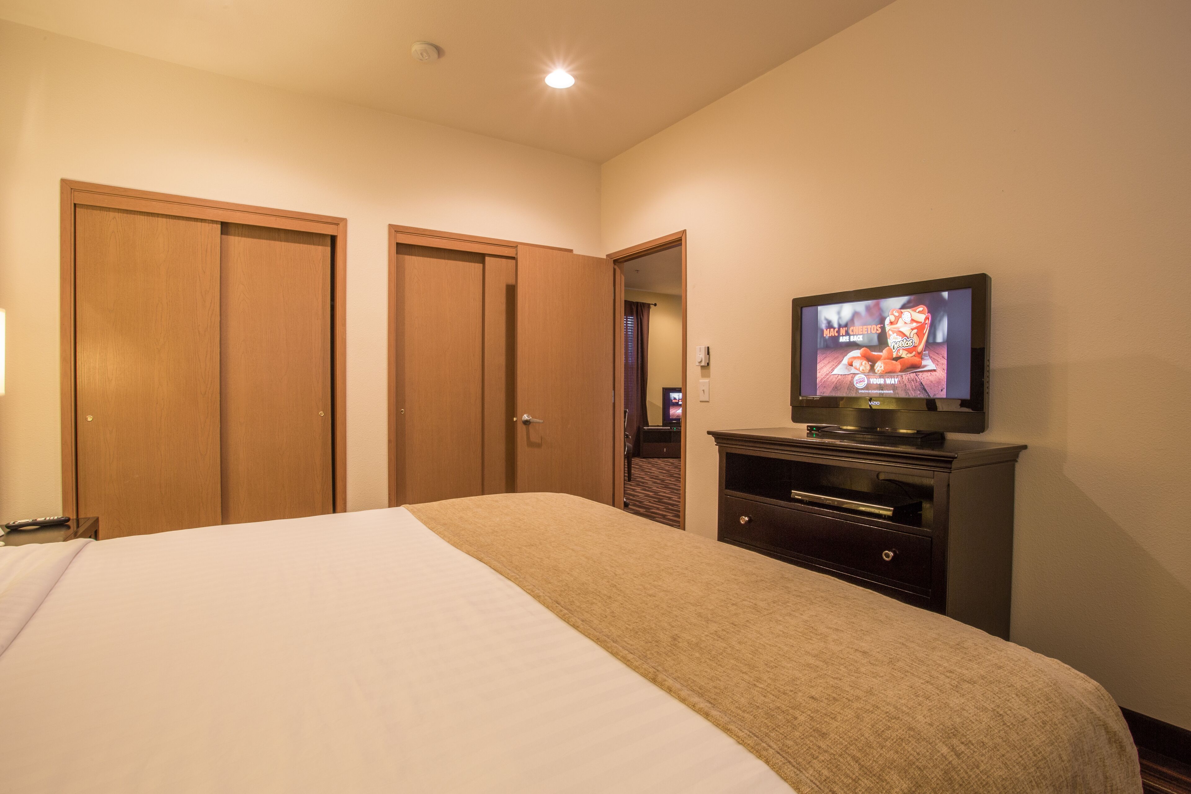 Quarto de hotel com cama, televisão e armários de madeira.