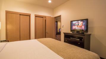 A hotel room with a bed, a television, and wooden wardrobes.