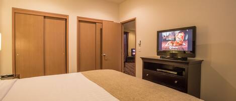 Quarto de hotel com cama, televisão e armários de madeira.