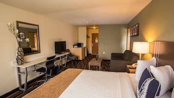 Een hotelkamer met een bed, bureau, stoel, televisie en een klein tafeltje.