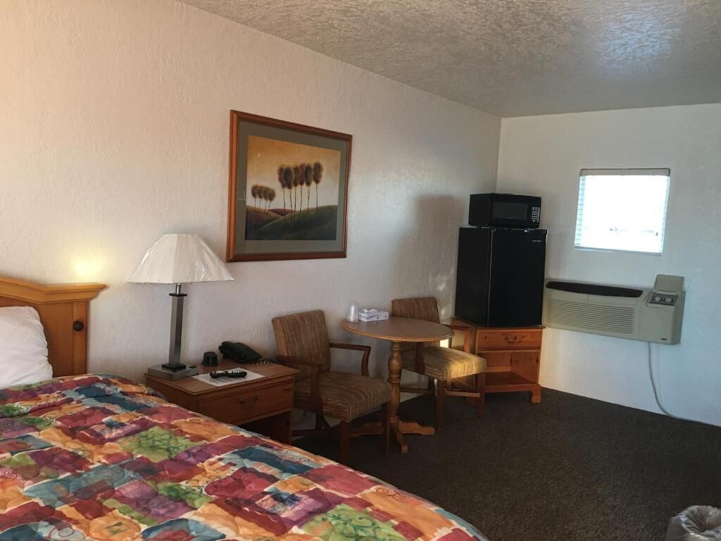 Ett hotellrum med en säng, ett skrivbord, en stol, en tv och ett fönster.