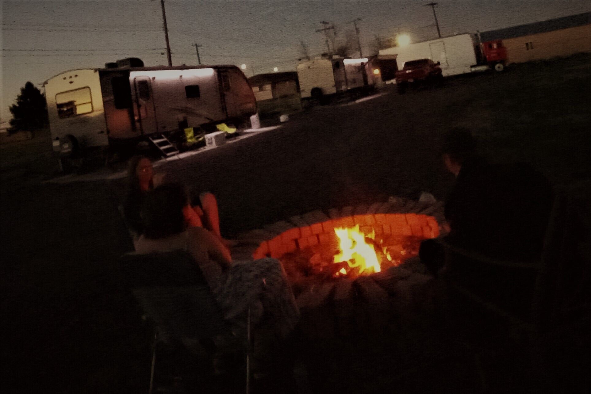Un camping con vehículos recreativos y una fogata.