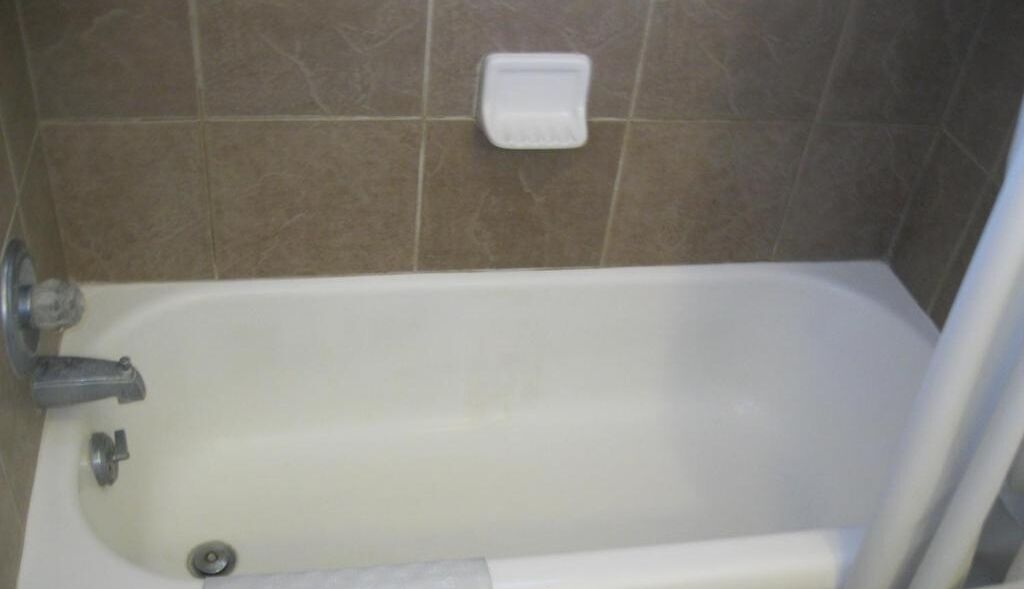 Eine Badewanne mit Wasserhahn und einer Seifenschale an der Wand.