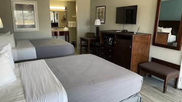 A hotel room with two beds, a desk, a TV, a mirror, and a microwave.
