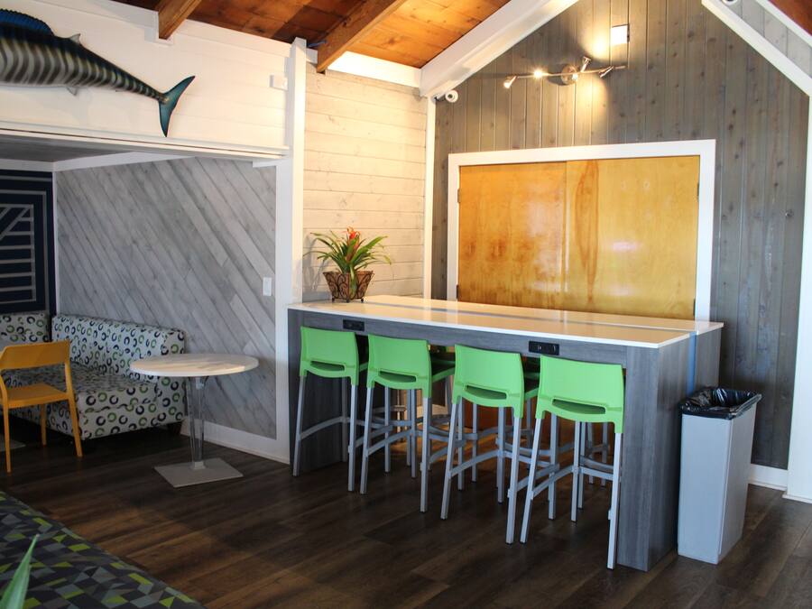 Une cuisine moderne avec un coin bar, des tabourets de bar verts et un plafond en bois.