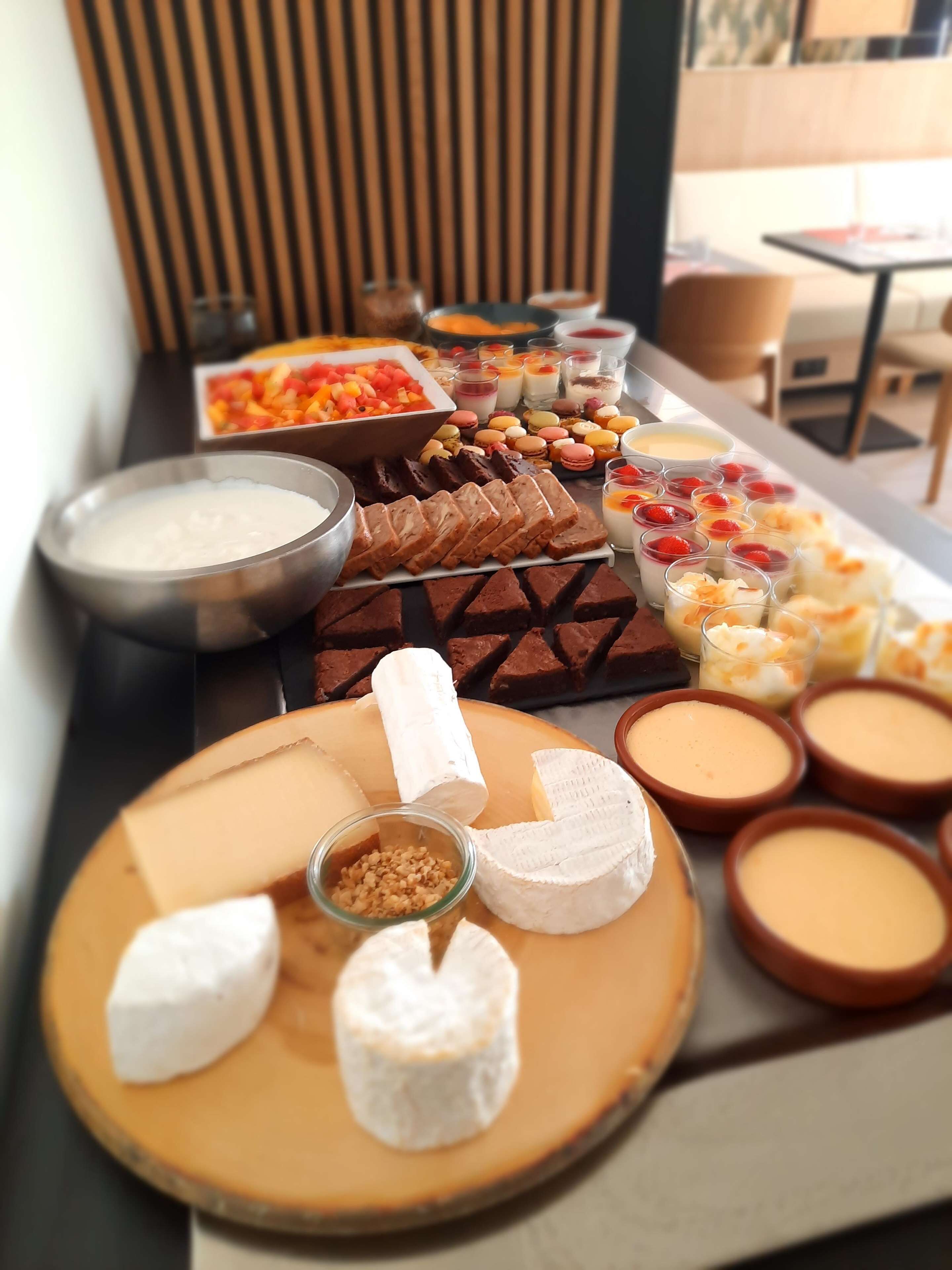 A buffet table with various food items including cheeses, fruits, and desserts.