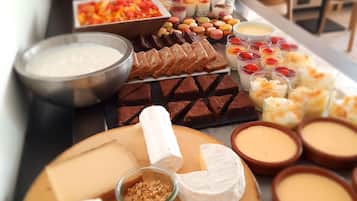 A buffet table with various food items including cheeses, fruits, and desserts.