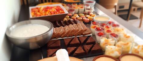 A buffet table with various food items including cheeses, fruits, and desserts.