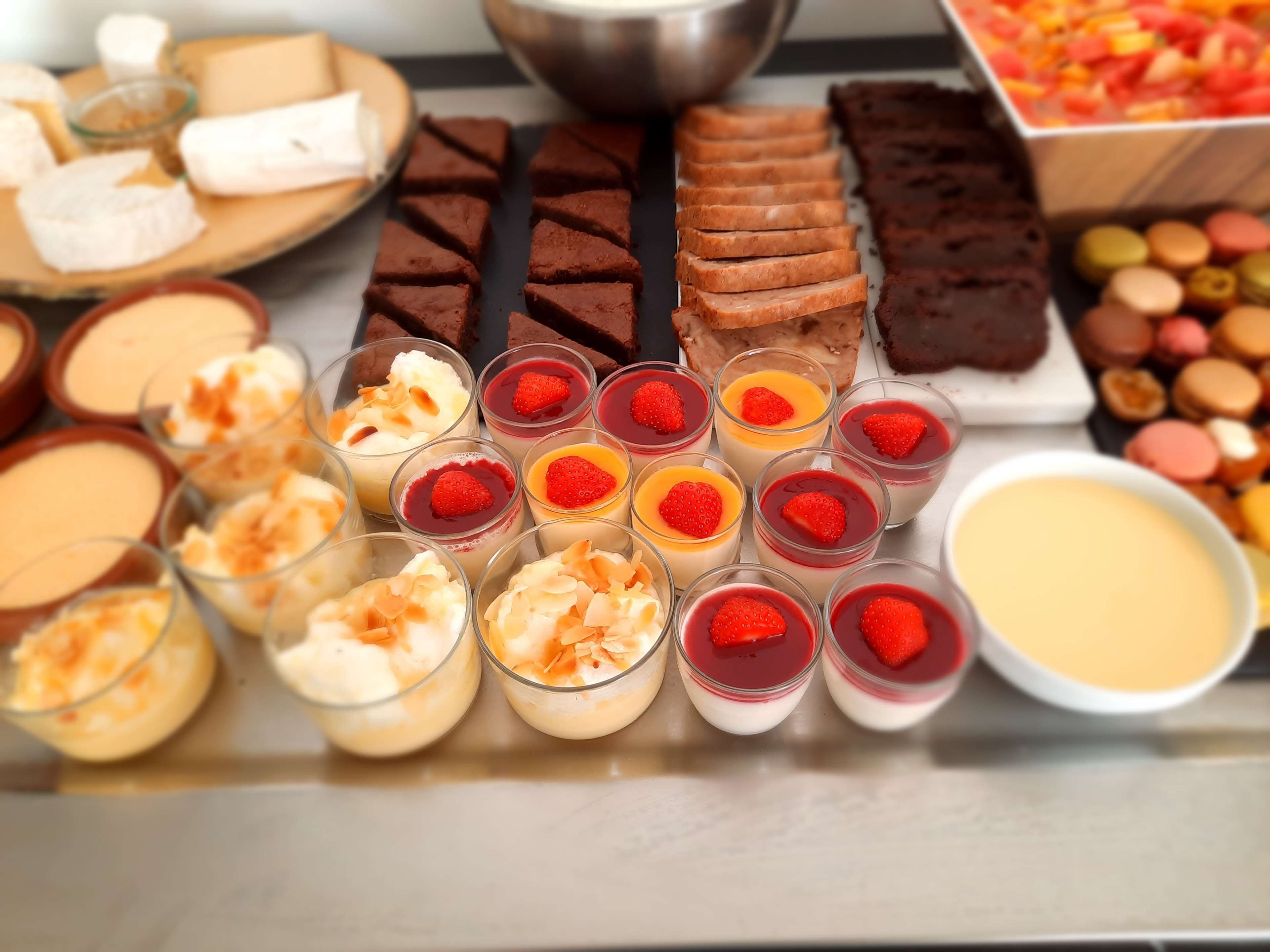 Verschiedene Desserts, darunter Brownies, Käsekuchen und Puddings mit Früchten.