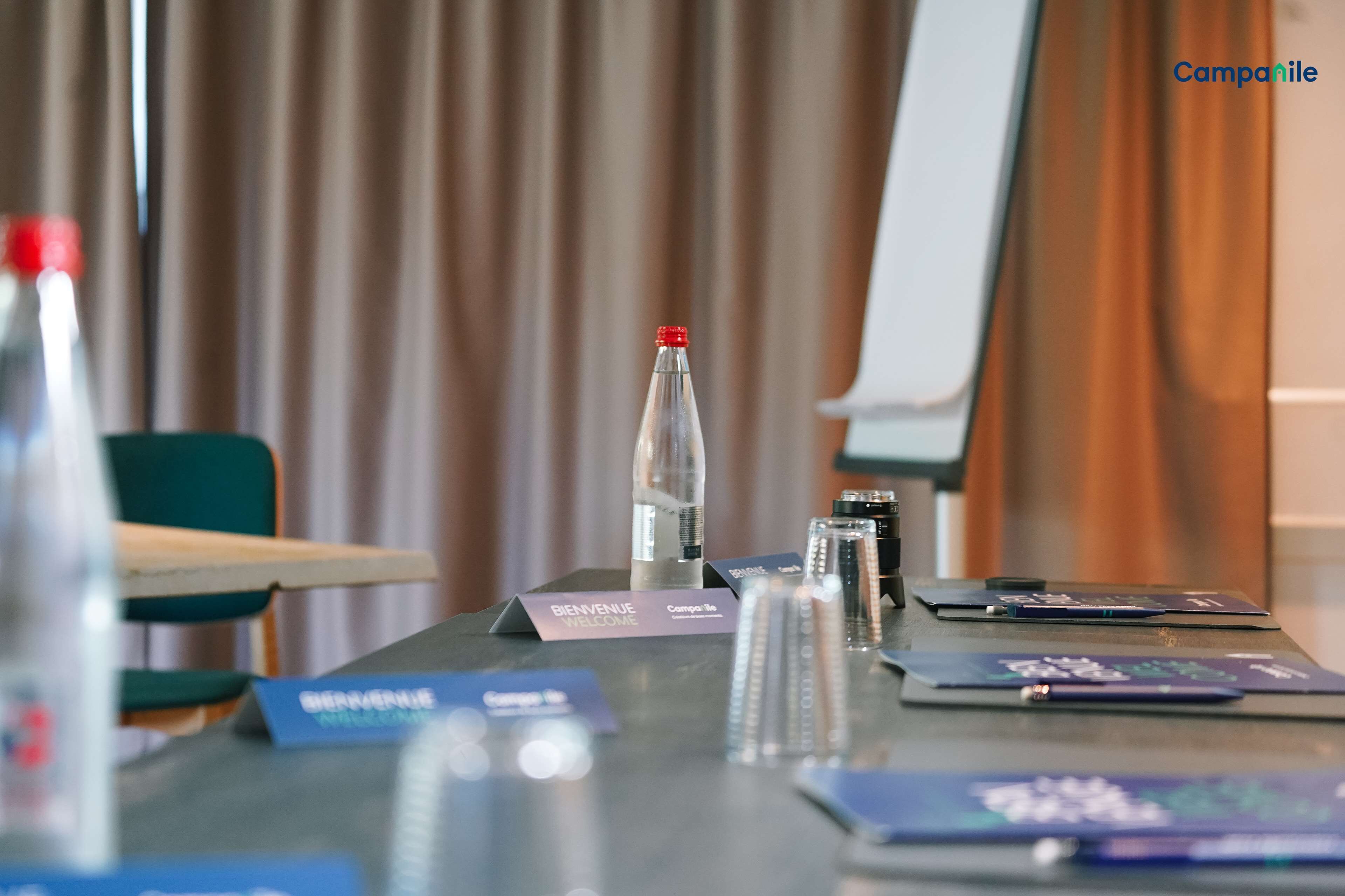 A conference table with nameplates, a bottle of water, and a whiteboard in a meeting room.